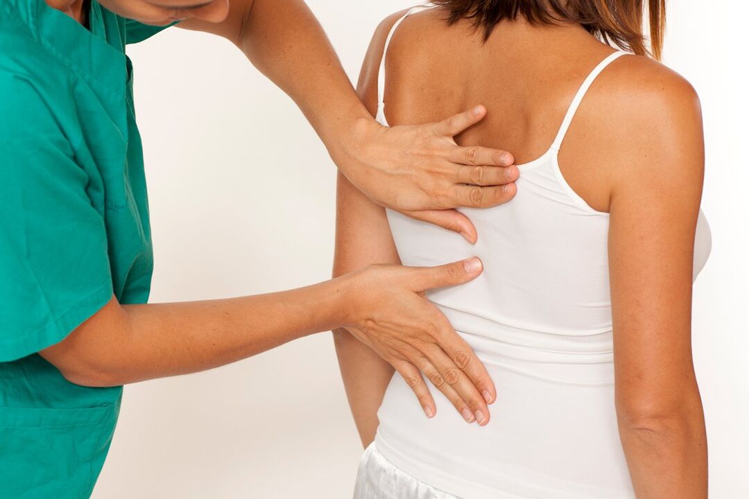 the doctor examines the back for pain in the shoulder blades